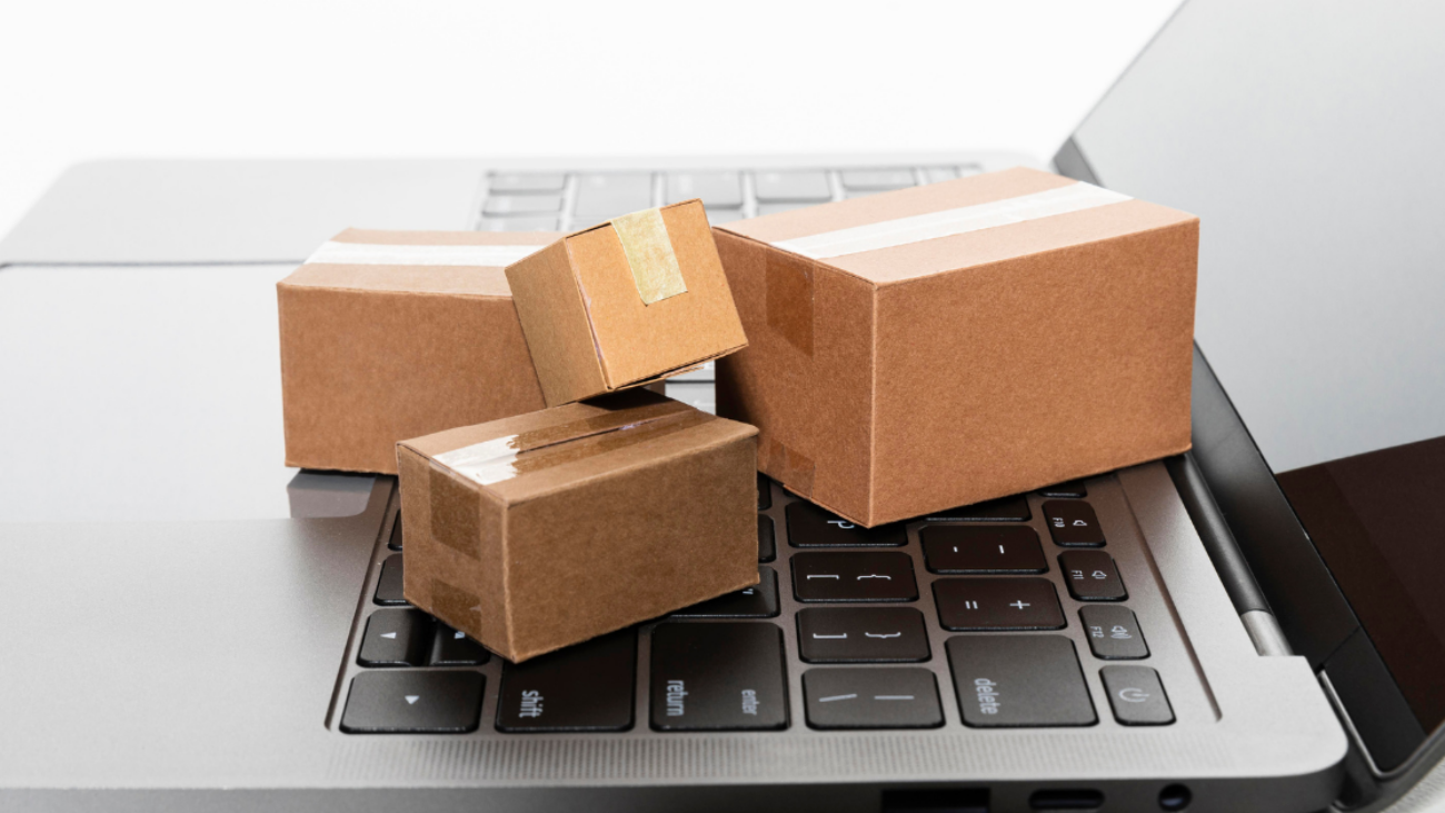 Four small cardboard packages placed on a laptop keyboard, representing logistics and procurement.