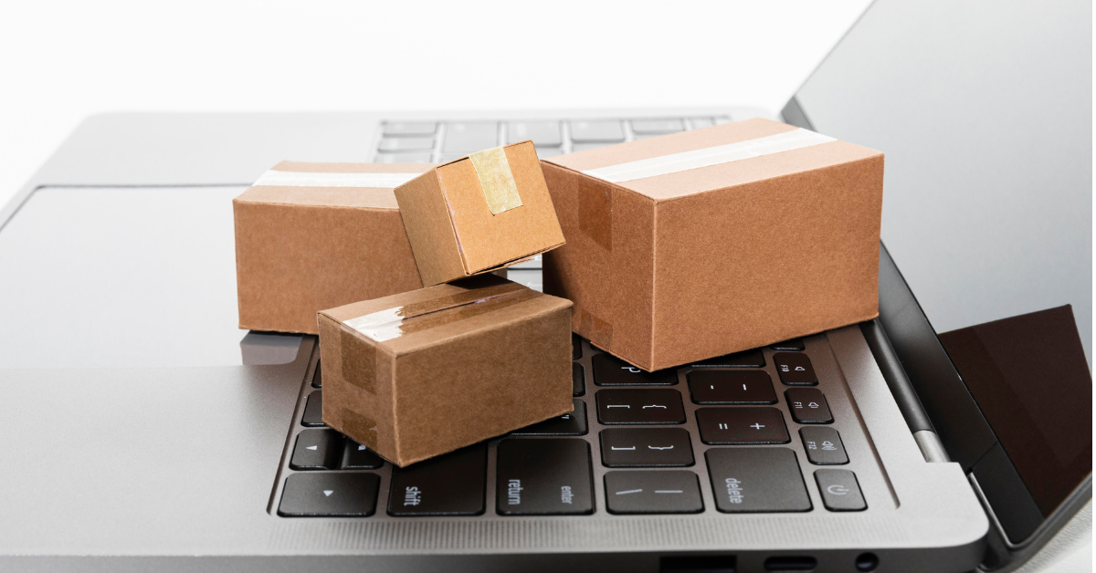 Four small cardboard packages placed on a laptop keyboard, representing logistics and procurement.